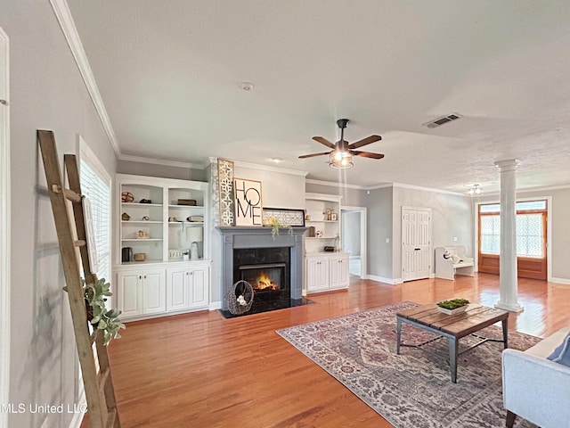 living room with a high end fireplace, ornate columns, ornamental molding, ceiling fan, and wood-type flooring