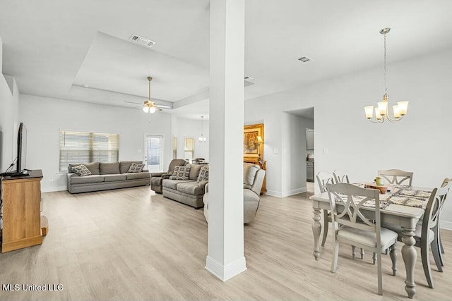 living room featuring ceiling fan with notable chandelier and light hardwood / wood-style floors