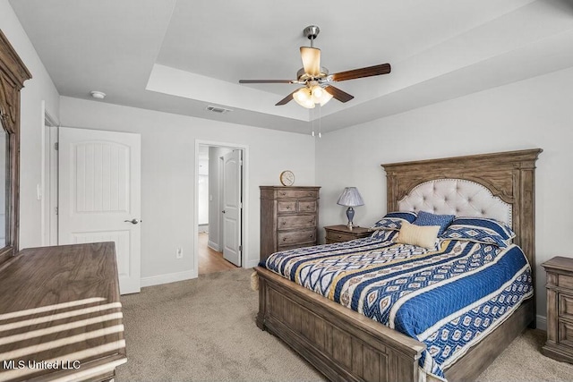 carpeted bedroom featuring a raised ceiling and ceiling fan