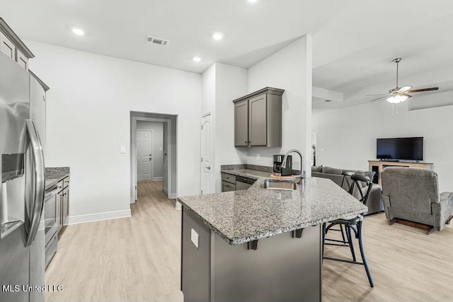 kitchen featuring appliances with stainless steel finishes, sink, a breakfast bar area, kitchen peninsula, and light hardwood / wood-style flooring