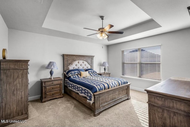 bedroom with a tray ceiling, light colored carpet, and ceiling fan