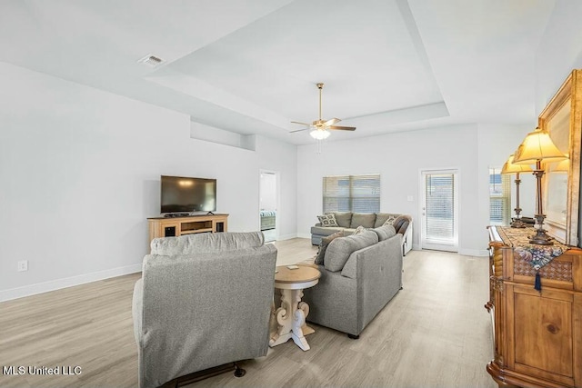 living room featuring ceiling fan, a raised ceiling, and light hardwood / wood-style flooring