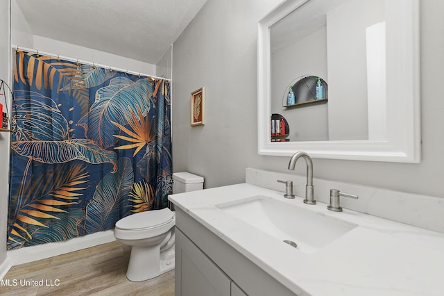 bathroom featuring vanity, wood-type flooring, a textured ceiling, and toilet