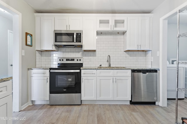 kitchen featuring decorative backsplash, white cabinetry, sink, and stainless steel appliances