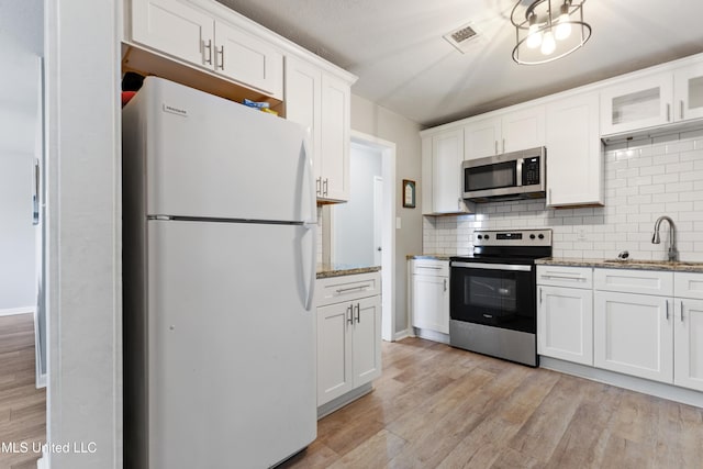 kitchen with sink, light stone counters, backsplash, white cabinets, and appliances with stainless steel finishes