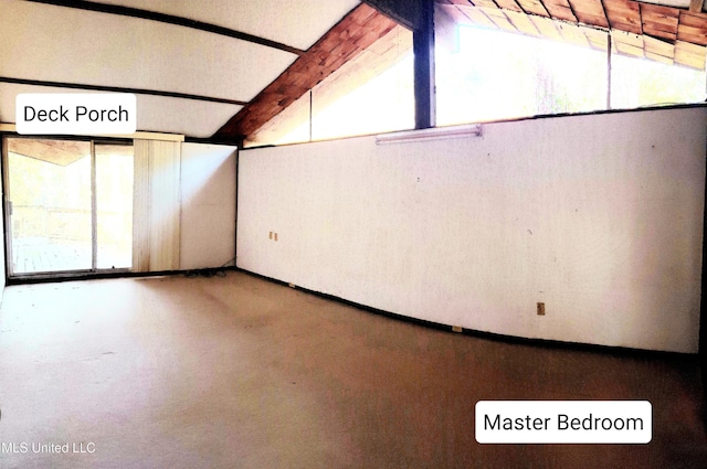 unfurnished room featuring vaulted ceiling with beams