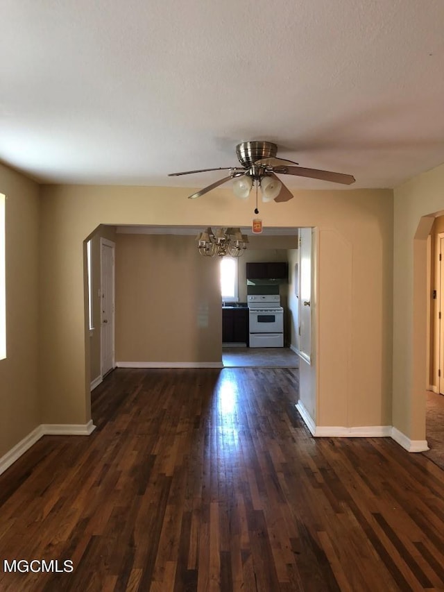 unfurnished living room featuring ceiling fan with notable chandelier and dark hardwood / wood-style flooring