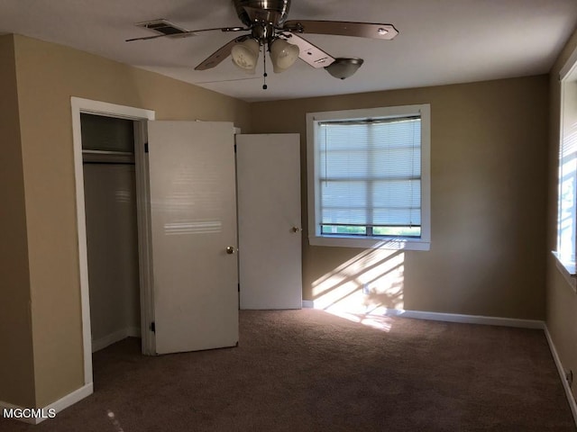 unfurnished bedroom with dark carpet, a closet, and ceiling fan