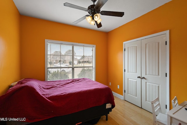 bedroom featuring a closet, baseboards, light wood-style flooring, and a ceiling fan