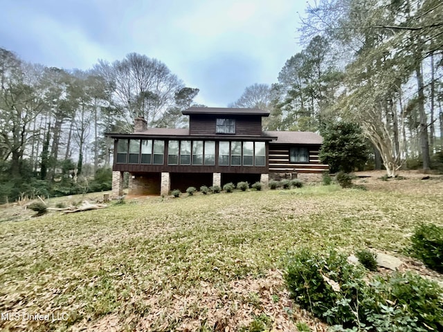 rear view of property featuring a sunroom and a lawn