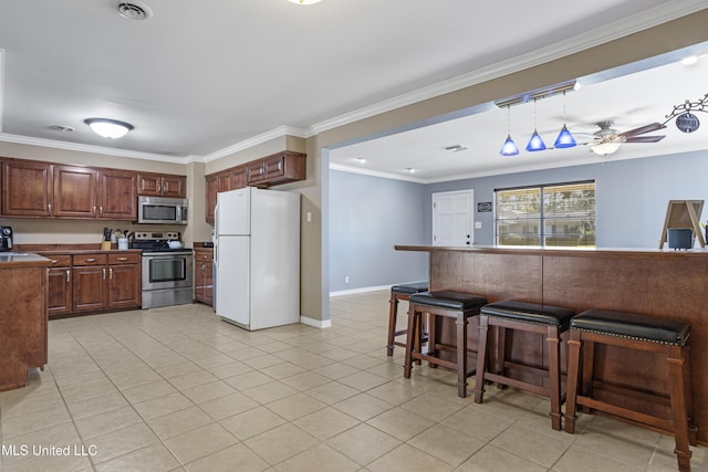 kitchen with hanging light fixtures, ceiling fan, ornamental molding, a kitchen bar, and stainless steel appliances