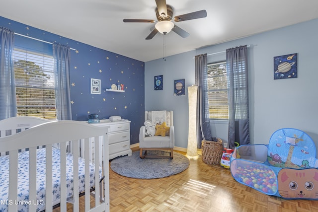 bedroom featuring parquet flooring, a nursery area, and ceiling fan