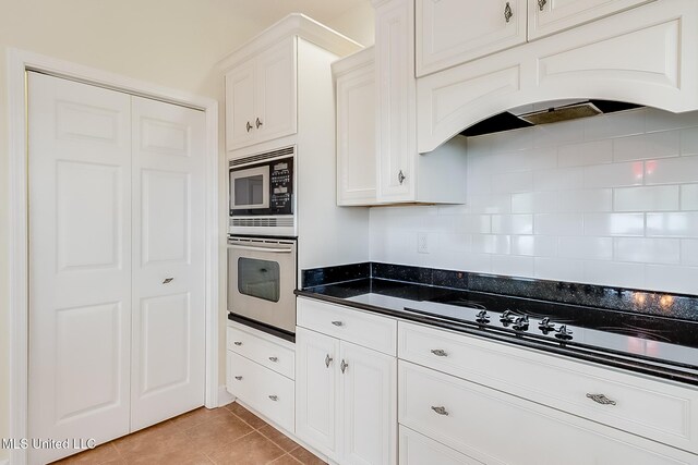 4013 Haiti St, Bay Saint Louis, MS 39520 - kitchen with decorative backsplash, appliances with stainless steel finishes, white cabinetry, and light tile patterned floors