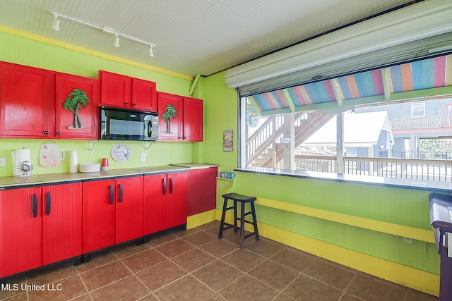 4013 Haiti St, Bay Saint Louis, MS 39520 - kitchen with track lighting, black microwave, red cabinetry, and plenty of natural light