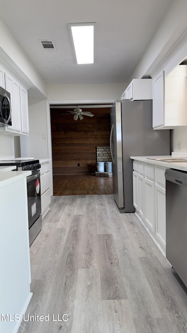 kitchen featuring white cabinets, stainless steel appliances, ceiling fan, and light hardwood / wood-style floors