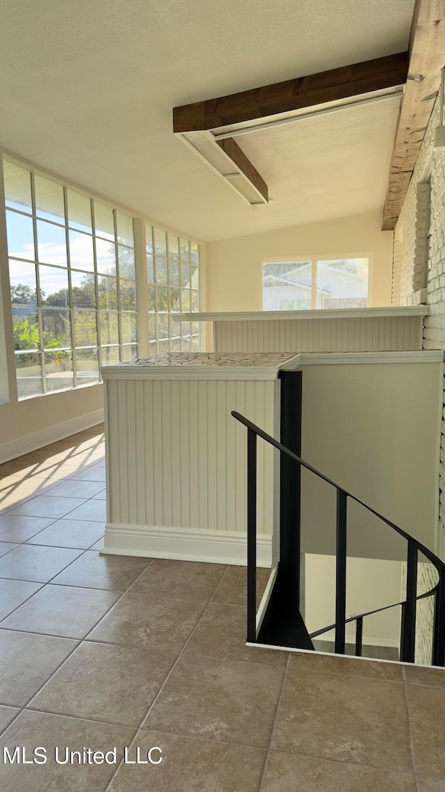 stairway featuring tile patterned flooring and beam ceiling