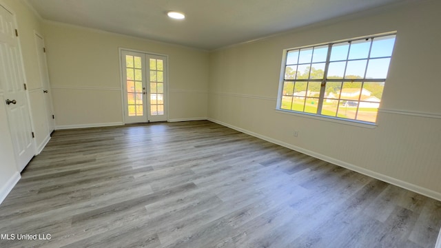 unfurnished room featuring french doors, ornamental molding, and light wood-type flooring