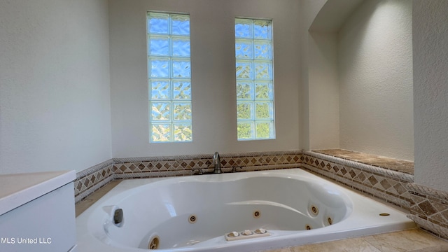 bathroom featuring a healthy amount of sunlight and tiled bath