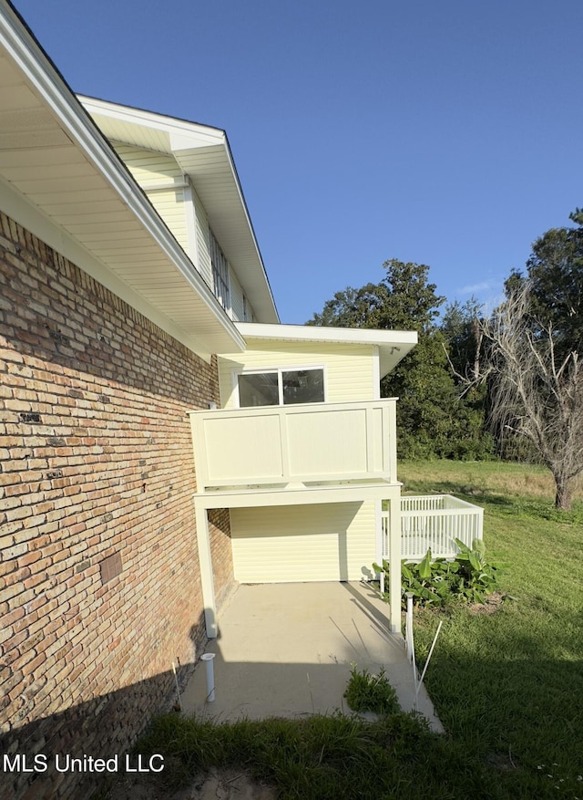 view of side of property featuring a balcony and a yard