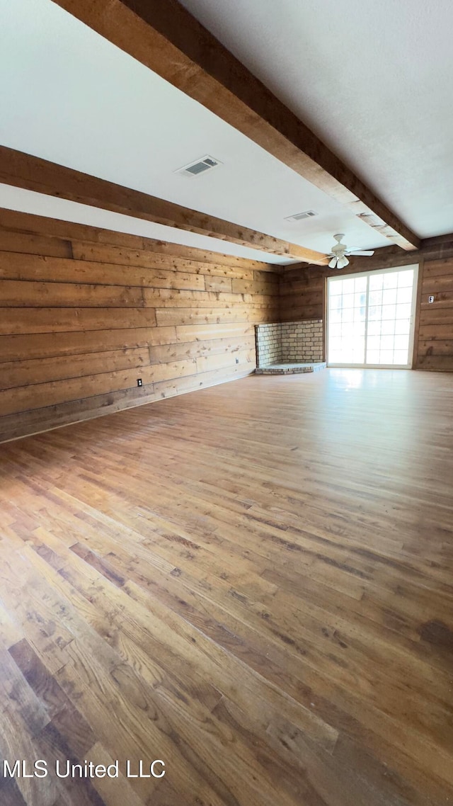 interior space featuring beam ceiling, wood walls, and wood-type flooring