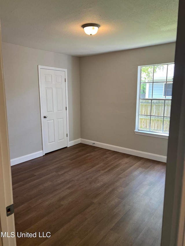 unfurnished room featuring a textured ceiling and dark hardwood / wood-style flooring