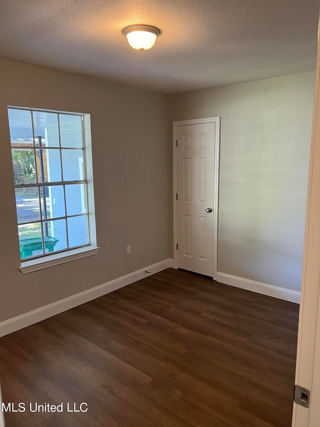 empty room with dark wood-type flooring and a textured ceiling