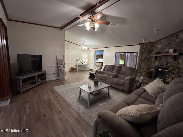 living room with hardwood / wood-style floors, lofted ceiling with beams, ornamental molding, and a stone fireplace