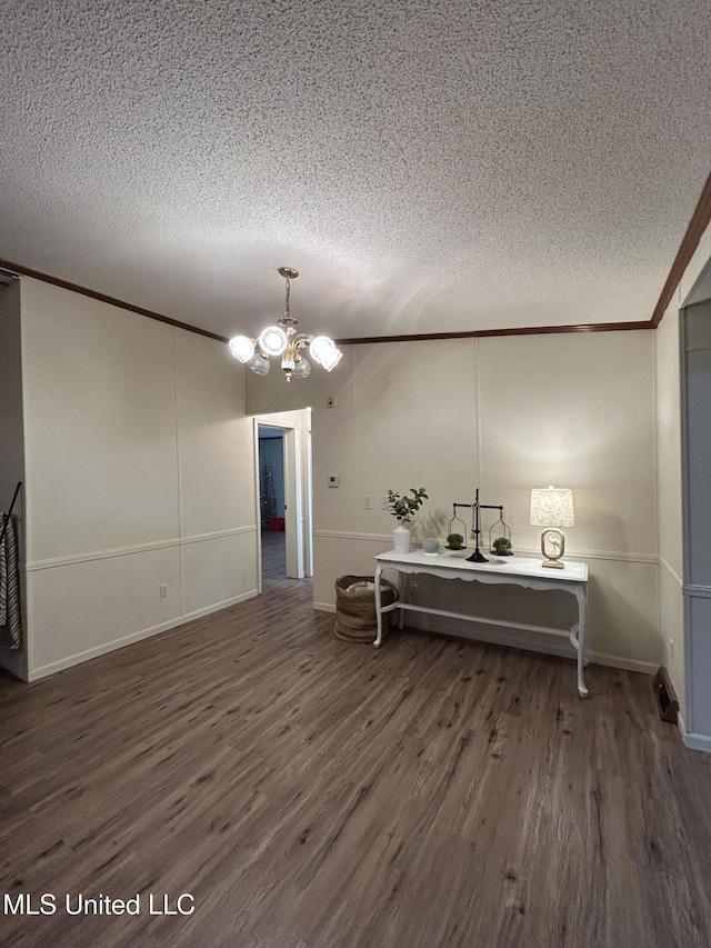 interior space featuring a notable chandelier, a textured ceiling, dark hardwood / wood-style flooring, and ornamental molding