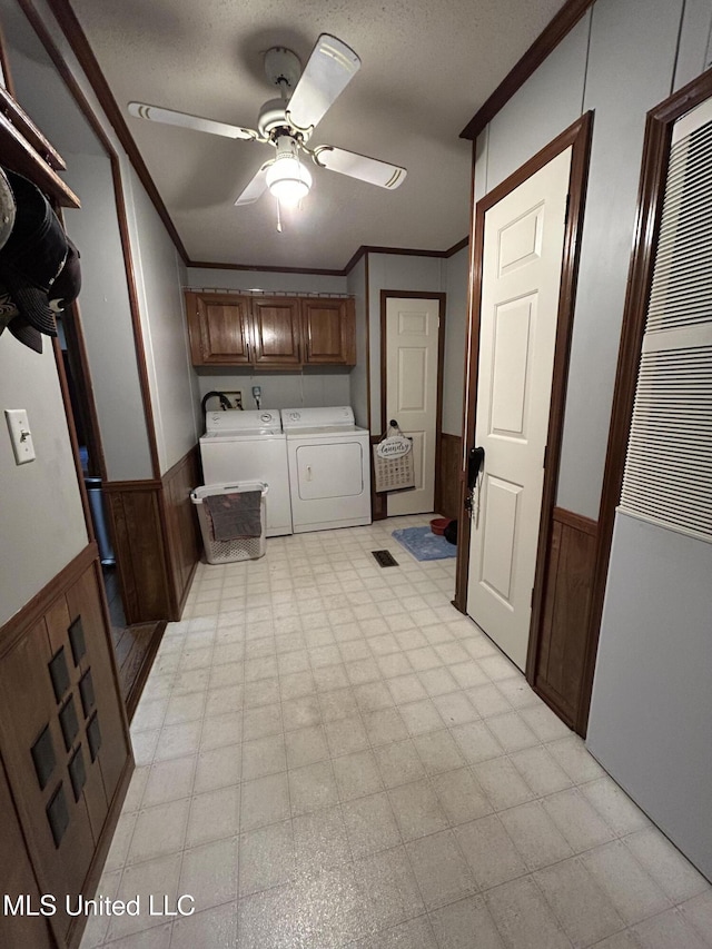 laundry area featuring ceiling fan, separate washer and dryer, crown molding, and cabinets