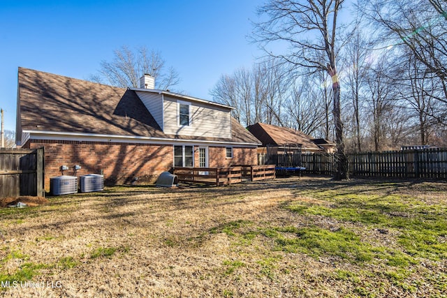 back of house featuring a trampoline, central AC unit, and a yard