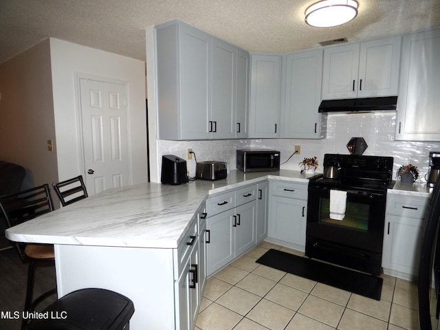 kitchen featuring tasteful backsplash, kitchen peninsula, a breakfast bar area, and black appliances