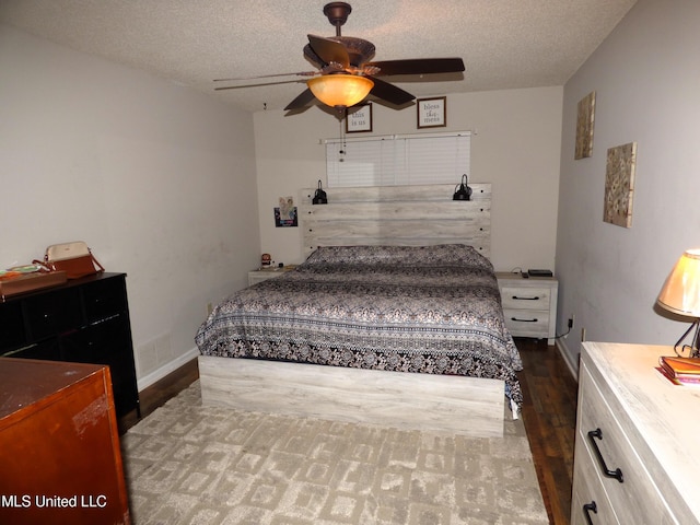 bedroom with ceiling fan, dark hardwood / wood-style floors, and a textured ceiling