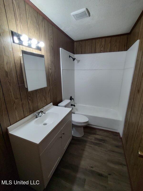 full bathroom featuring vanity, shower / tub combination, hardwood / wood-style flooring, toilet, and a textured ceiling