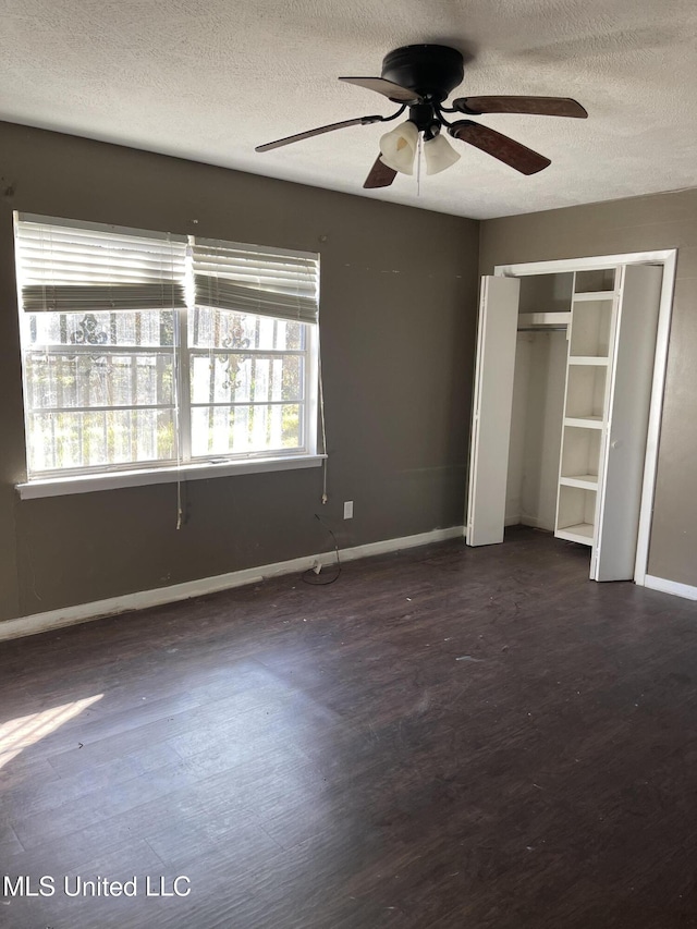 unfurnished bedroom with ceiling fan, dark hardwood / wood-style flooring, and a textured ceiling