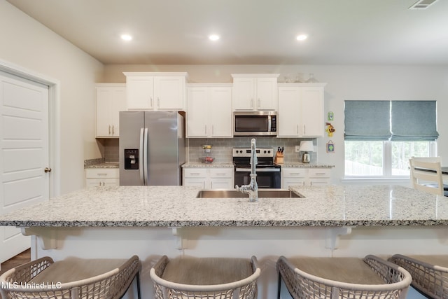 11625 Talla Dr, Ocean Springs, MS 39564 - kitchen featuring stainless steel appliances, decorative backsplash, white cabinets, a kitchen breakfast bar, and recessed lighting