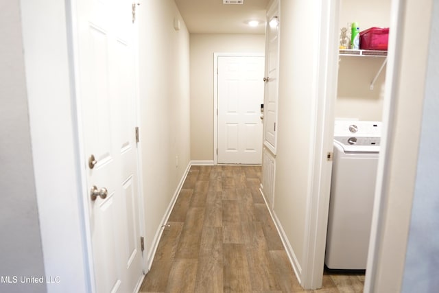 hallway featuring washer / dryer, visible vents, baseboards, and wood finished floors