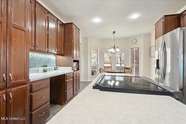 kitchen with tasteful backsplash, appliances with stainless steel finishes, decorative light fixtures, and a notable chandelier