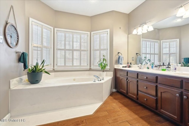 bathroom with wood-type flooring, a bathing tub, and vanity