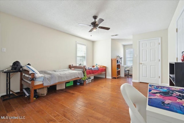 bedroom with hardwood / wood-style flooring, ceiling fan, and a textured ceiling