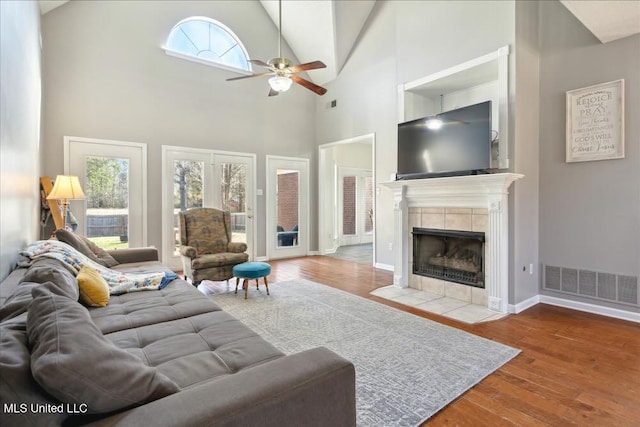 living room with vaulted ceiling, ceiling fan, hardwood / wood-style floors, and a tile fireplace