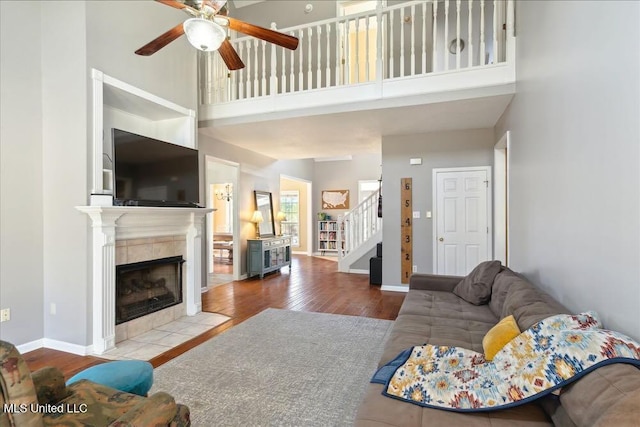 living room with a fireplace, a towering ceiling, light hardwood / wood-style flooring, and ceiling fan