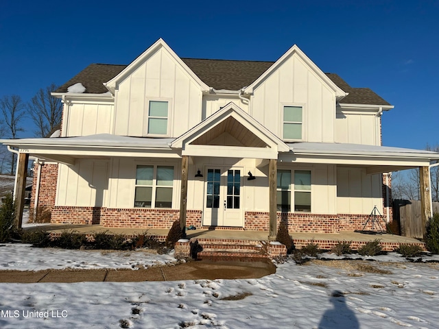 view of front of property featuring roof with shingles, brick siding, board and batten siding, and french doors