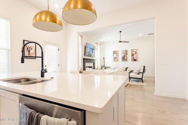 kitchen with a fireplace, light wood-style floors, open floor plan, a sink, and dishwasher