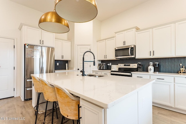 kitchen featuring light wood finished floors, appliances with stainless steel finishes, white cabinets, and a sink