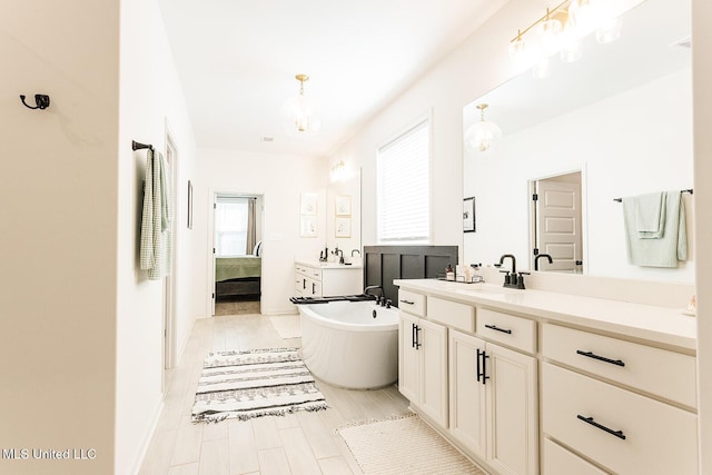 bathroom featuring a freestanding bath, wood finished floors, two vanities, and connected bathroom