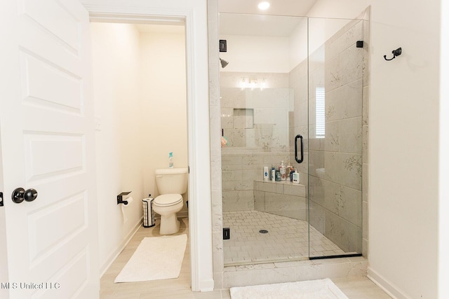 bathroom featuring toilet, a shower stall, and baseboards