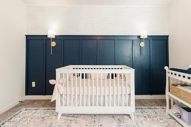 carpeted bedroom featuring a nursery area, a wainscoted wall, and a decorative wall