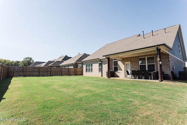 rear view of house featuring brick siding, a lawn, a patio area, and a fenced backyard