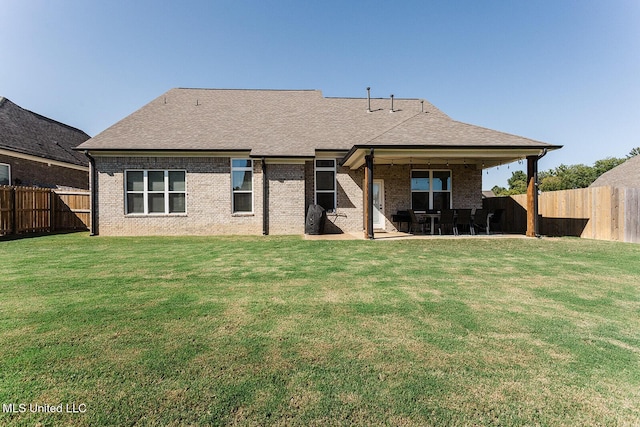 rear view of property featuring roof with shingles, a fenced backyard, a yard, and a patio