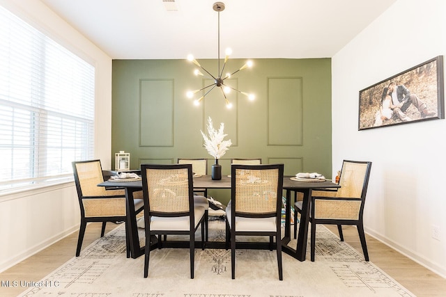 dining space featuring baseboards, a notable chandelier, and light wood finished floors